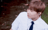 a young man wearing ear buds and a white shirt with a tie