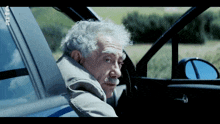 a man with gray hair and a mustache is sitting in a car with a sticker on the side that says rtl