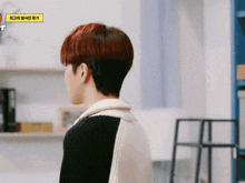 a man with red hair is standing in front of a yellow sign that says ' t ' on it