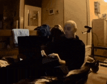 a bald man sits on a couch using a laptop
