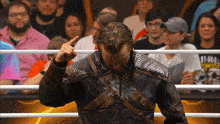 a man in a leather jacket is standing in front of a crowd and giving the middle finger