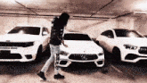 a man is standing in front of a row of white cars in a garage .