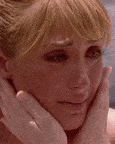 a close up of a woman covering her mouth with her hands