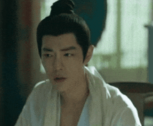 a man with a bun on his head is sitting in a chair
