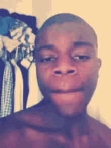 a man without a shirt is making a funny face in front of a closet full of clothes
