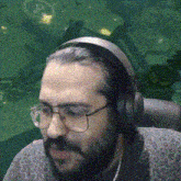 a man with a beard wearing headphones and glasses is sitting in a chair .