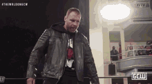 a man in a leather jacket is standing in a ring with the word fite on the bottom
