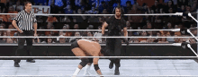 a wrestler is kneeling down in a wrestling ring with a referee standing behind him .