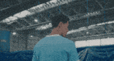 a man in a blue shirt with a white stripe on the sleeve is standing in a warehouse