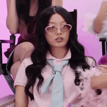 a woman wearing sunglasses and a tie is sitting in a director 's chair