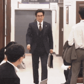 a man in a suit and tie is walking through a hallway