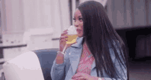 a woman is sitting at a table drinking a glass of wine .