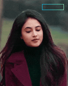 a woman wearing a black turtleneck and a red coat is looking down