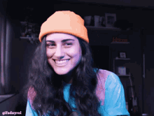 a woman wearing an orange beanie and a blue shirt with gifsdayrol written below her