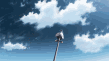 a clock on a pole against a blue sky with white clouds