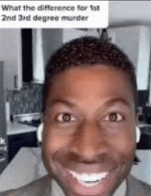 a man wearing headphones is smiling and making a funny face in a kitchen .