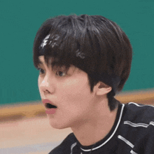 a young man wearing a headband and a black shirt looks surprised .