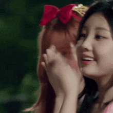 a woman with a red bow in her hair is standing next to another woman .