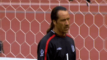 a man wearing a number 1 jersey stands in front of a goal
