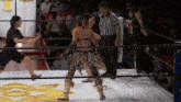a woman in a wrestling ring with a referee and a sign that says fpwmg