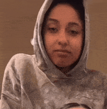 a woman wearing a hoodie is making a funny face and smiling .