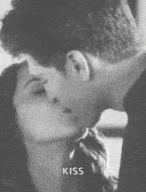 a man and a woman kissing in a black and white photo .