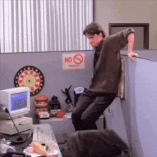 a man leans against a cubicle wall with a no smoking sign on it