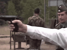 a man in a white shirt is pointing a gun at a soldier