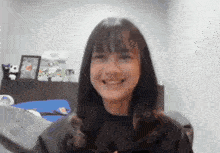 a girl is smiling in a room with stuffed animals on the shelf