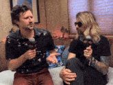 two men are sitting on a couch and one is holding a microphone that says ' abc ' on it