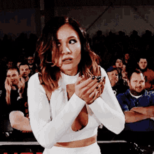a woman in a white crop top is standing in front of a crowd of people