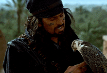 a man with a tattoo on his face holds a bird in his hand