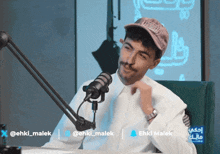 a man sitting in front of a microphone with the name ehki malek on the bottom