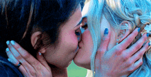 two women are kissing each other with their hands on their faces