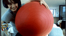 a boy wearing headphones holds a red exercise ball