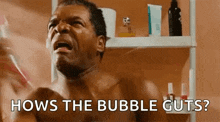 a shirtless man is brushing his teeth in front of a mirror in a bathroom and asking how the bubble guts .