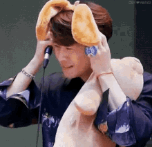 a man is holding a stuffed animal in front of a microphone while wearing bunny ears .