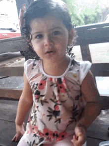 a little girl wearing a pink and white floral dress