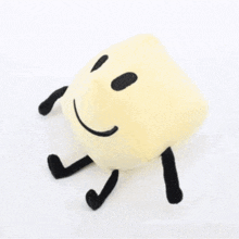 a stuffed animal with a smiley face and black arms and legs is standing on a white background .