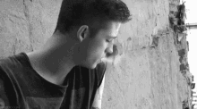 a black and white photo of a young man smoking a cigarette .