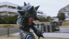 a monster with spikes on it 's head and arms is standing in front of a building