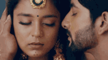 a man is kissing a woman on the forehead with closed eyes