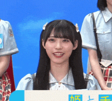 a girl with long black hair is smiling while holding a sign that says ' a ' on it