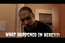 a man is standing in front of a door with the words what happened in here written below him .