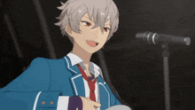 a boy in a blue suit and red tie is standing in front of a microphone