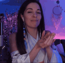 a woman wearing ear buds is clapping her hands in front of a dream catcher
