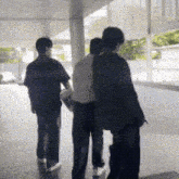 a group of people are walking down a hallway and one of them is carrying a skateboard .