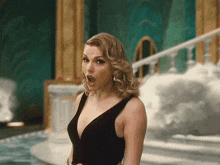 a woman in a black dress with a plunging neckline has her mouth open