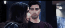 a man and a woman are looking at each other in a room .