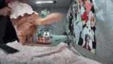 a cat wearing a pink dress is standing on a bed next to a bowl of food